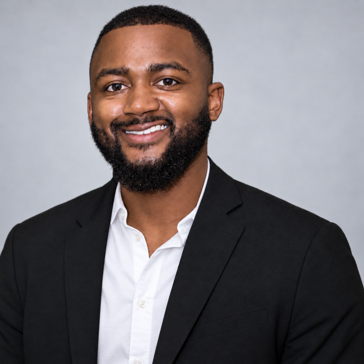 Da’Cor Wiggins smiling in a black blazer and white open-collar shirt